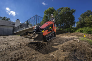 Ditch Witch mini skid steer working in wet, uneven soil during mud season to improve efficiency