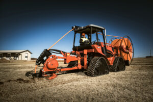 Ride-on trencher performing utility trenching work in challenging ground conditions