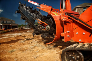 Close-up of a Ditch Witch trencher chain and digging system during a daily equipment inspection before trenching work
