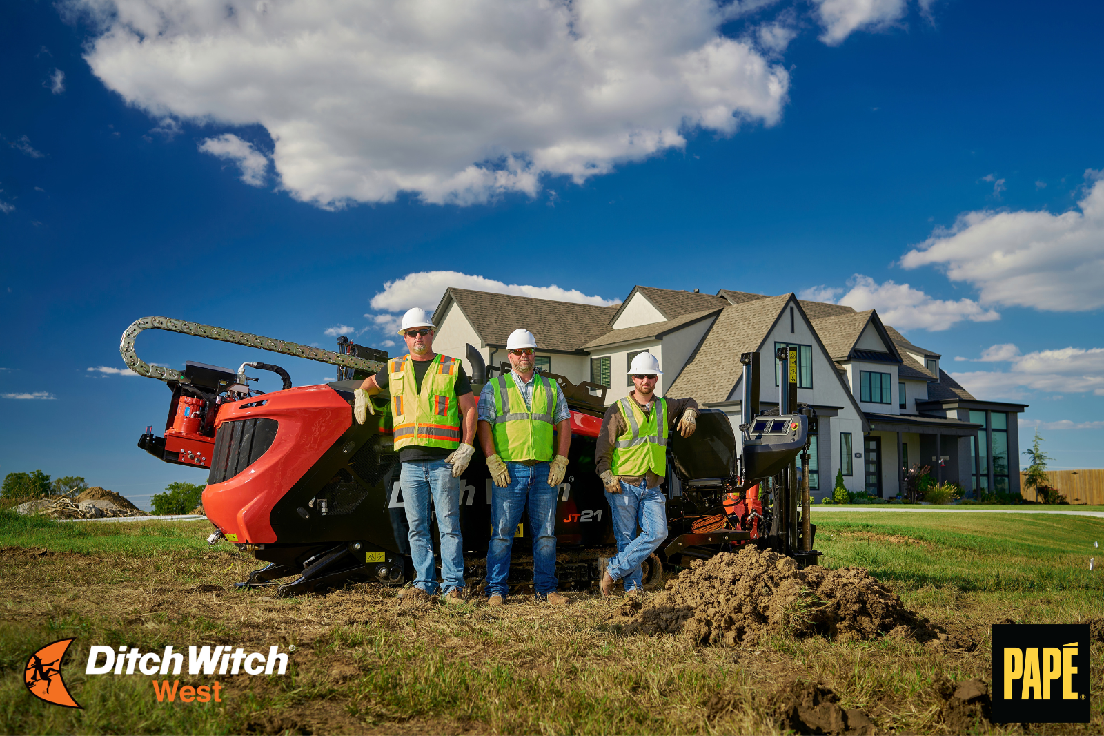 Three utility crew members standing with a Ditch Witch JT21 horizontal directional drill at a residential jobsite.