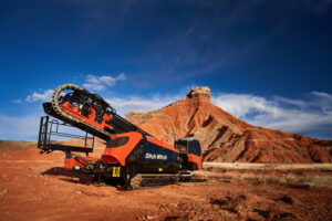 Ditch Witch AT120 horizontal directional drill positioned on a red dirt jobsite with rocky terrain in the background.